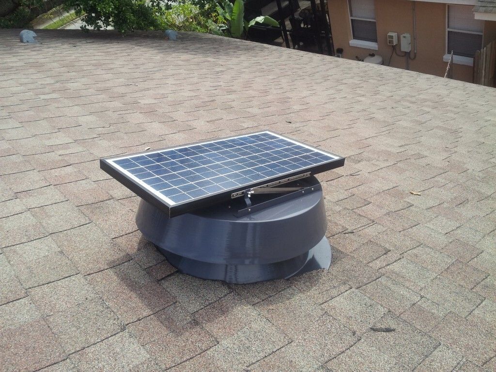 Gloved hand removing leaves from a gutter on a brick roof.