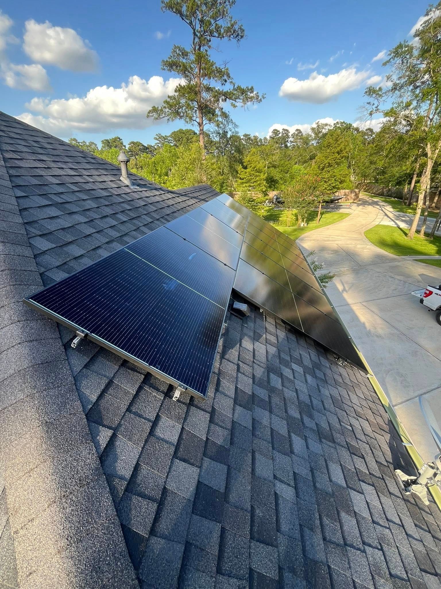 Solar panels installed on a dark gray shingle roof, angled toward the sun.