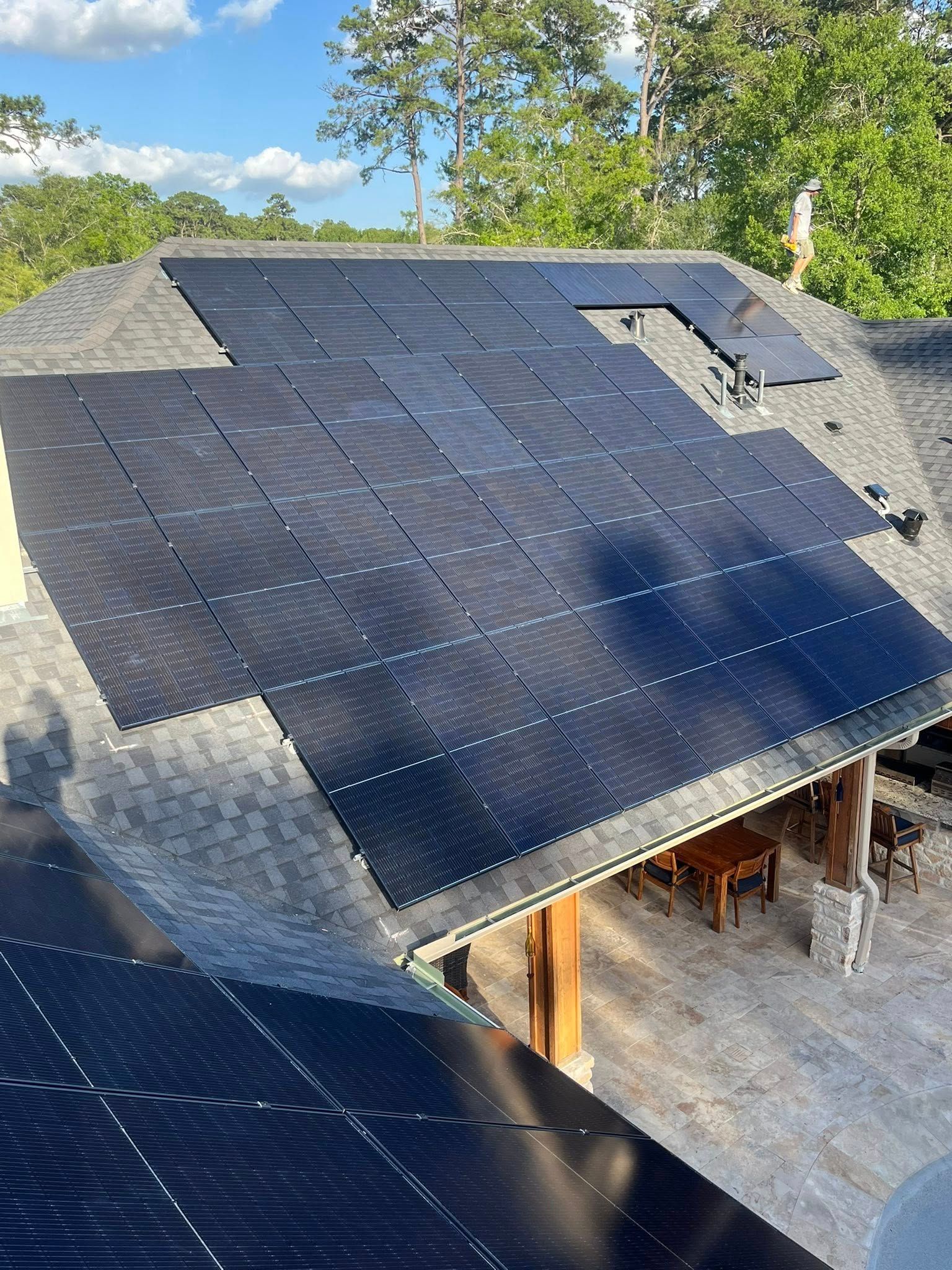 Solar panels installed on a dark gray shingle roof, outdoor setting.