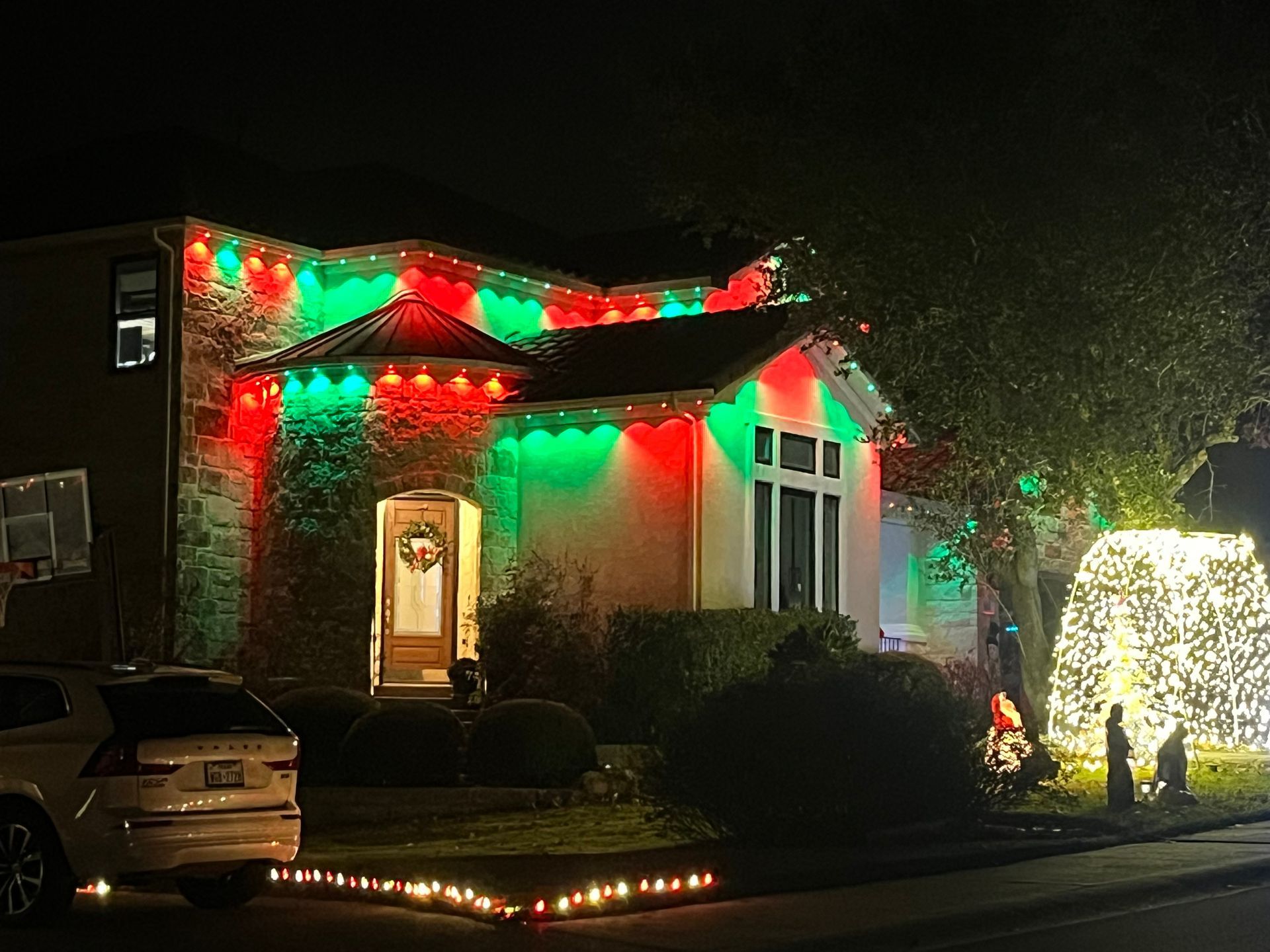 Christmas decorated doorway with wreaths and lights, framed by columns.