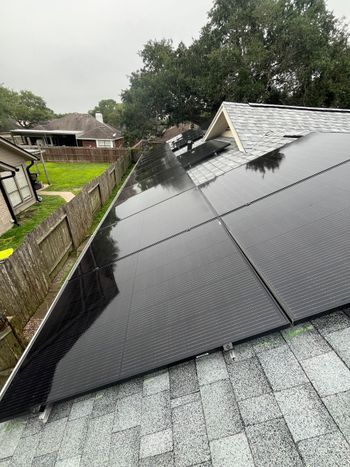 Person cleaning solar panels with a long-handled brush on a sunny day.