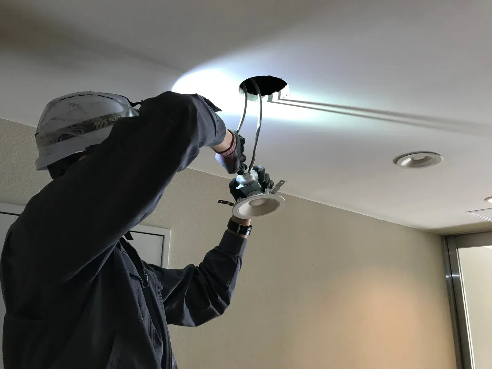 Solar panels installed on a corrugated metal roof against a backdrop of trees and a blue sky.