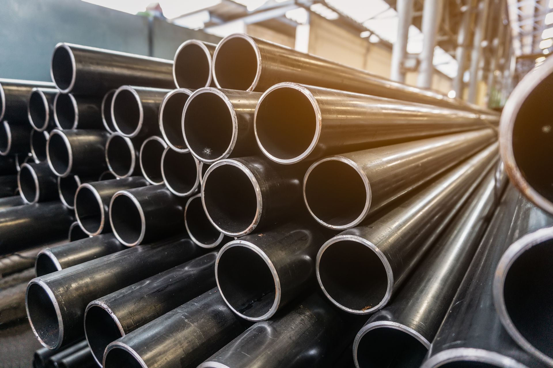 Close-up of galvanised steel pipes in a stack waiting for shipment in a warehouse.