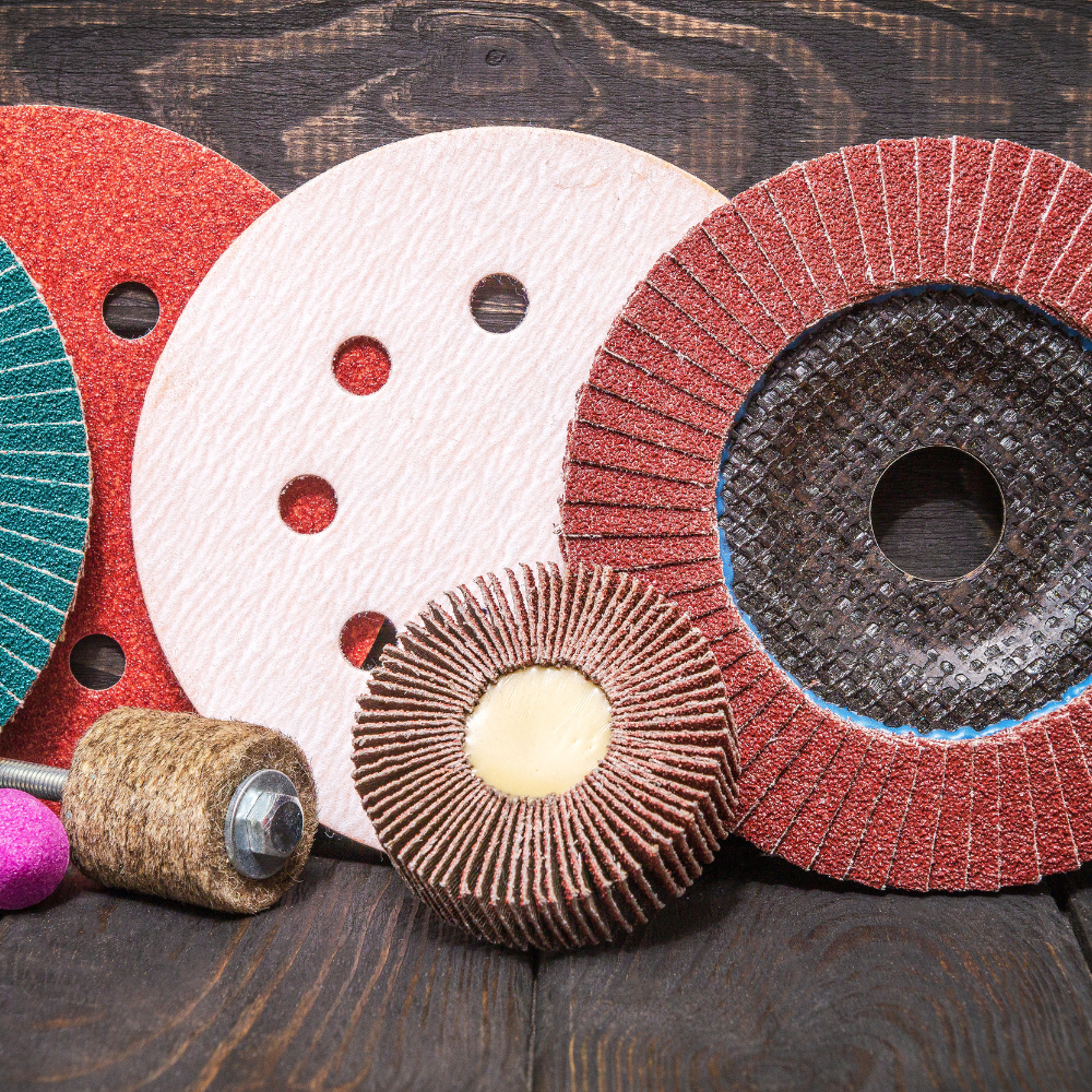 Grinding and sanding discs and abrasive tools in red, white, and brown on a wooden surface