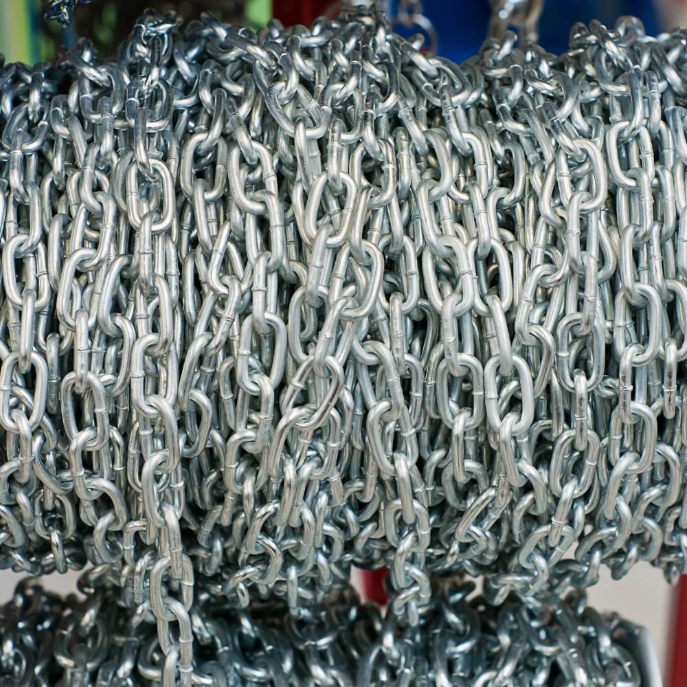 Coiled silver metal chain links stacked densely, with a blue background and a red hook visible