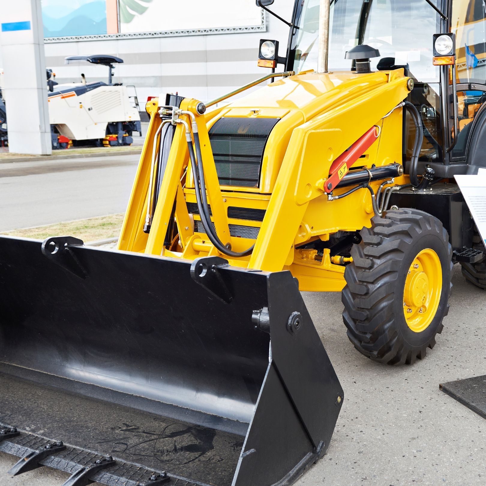Yellow tractor with a large black snowplow blade parked indoors