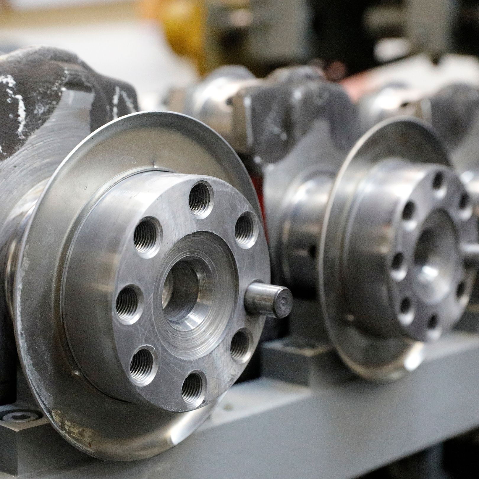 Close-up of shiny metal wheel hubs or brake rotors lined up on a factory conveyor