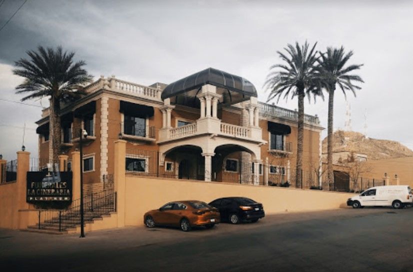 Un gran edificio con coches aparcados delante y palmeras.