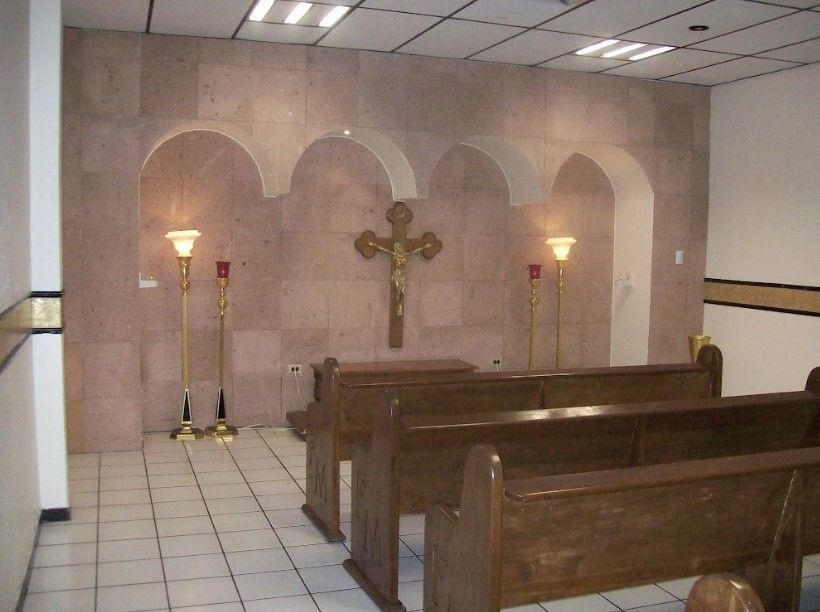 Una iglesia con bancos de madera y una cruz en la pared