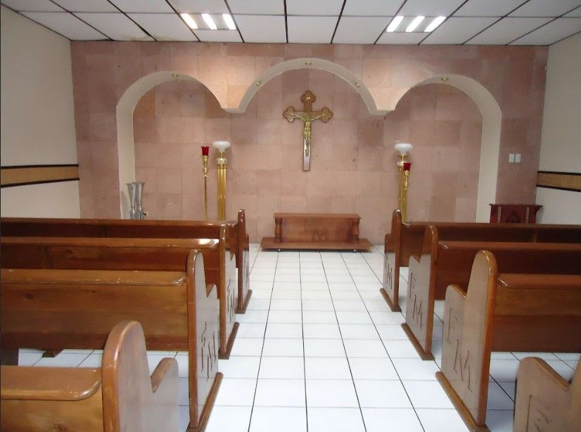 Una iglesia con bancos de madera y una cruz en la pared