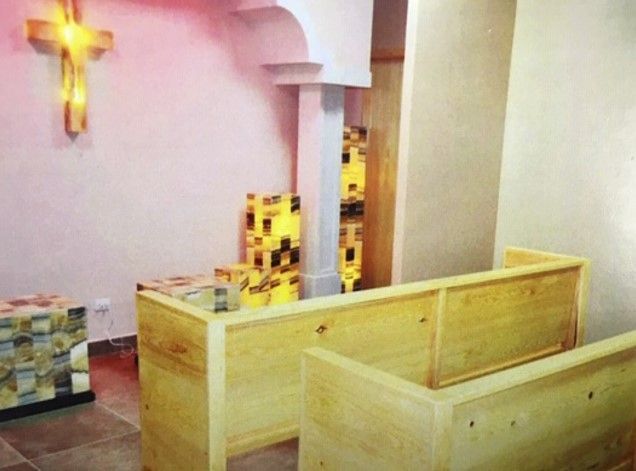 Una habitación con un banco de madera y una cruz en la pared.