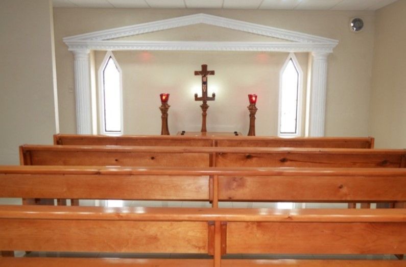 Una iglesia con bancos de madera y una cruz en la pared