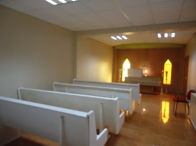 Una iglesia vacía con bancos blancos y una vidriera