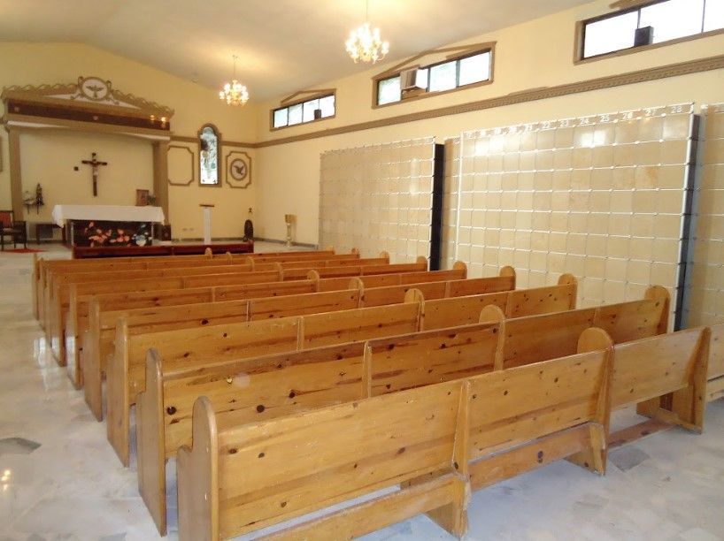 Filas de bancos de madera en una iglesia con una cruz en la pared
