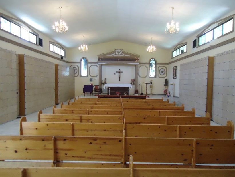 Una iglesia con bancos de madera y una cruz en la pared