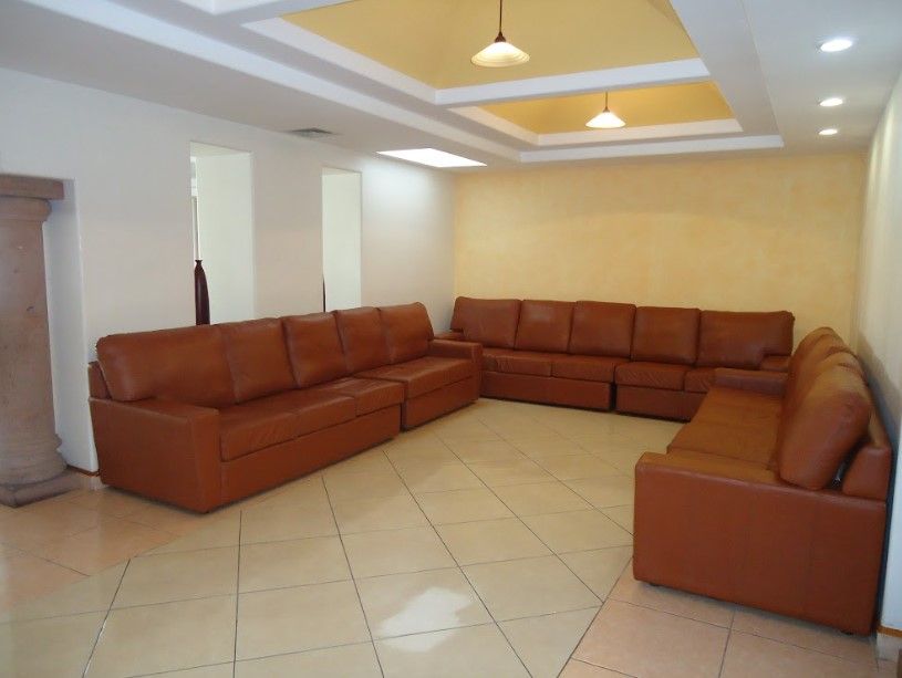 Una sala de estar con muchos sofás de cuero marrón.