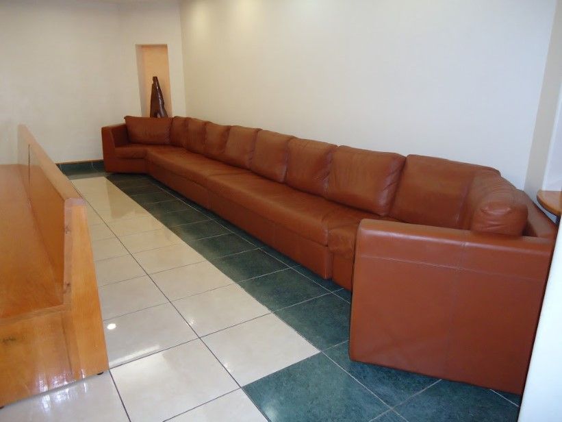 Un largo sofá de cuero marrón está en una sala de espera.