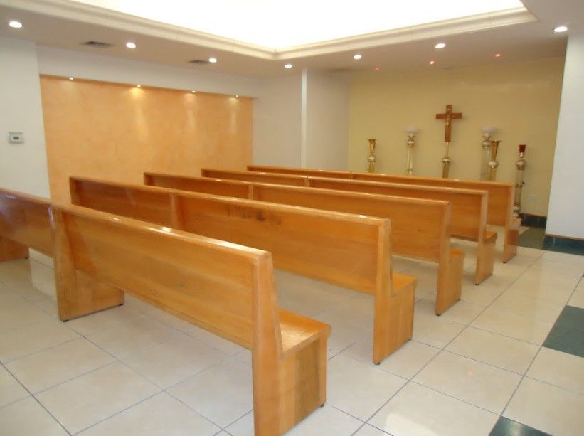 Una iglesia con bancos de madera y una cruz en la pared