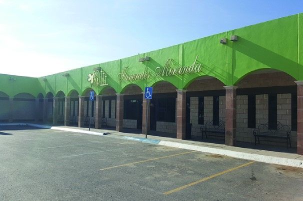 Un edificio verde con arcos y un lugar de estacionamiento para discapacitados.