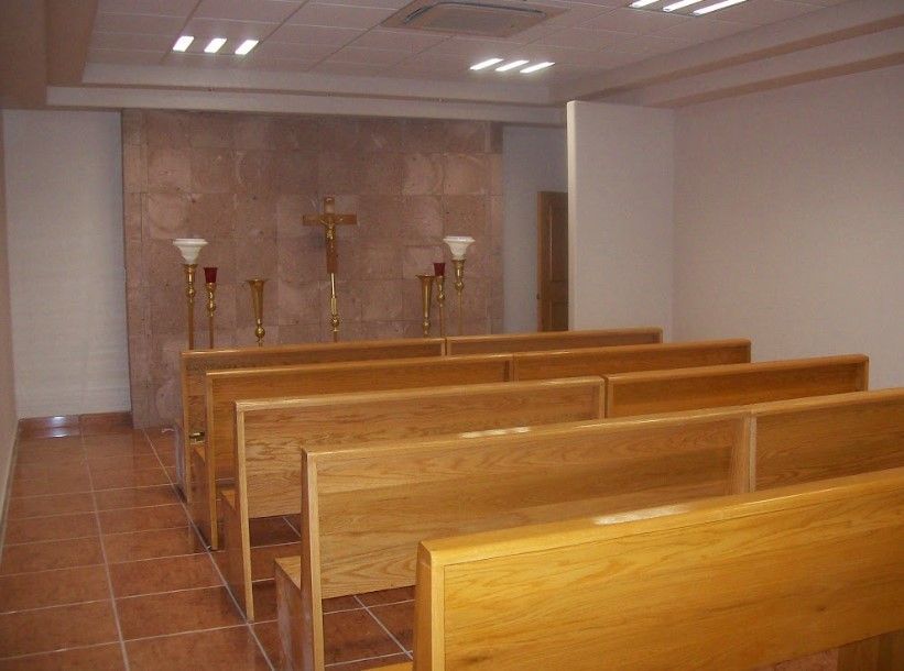 Una iglesia con bancos de madera y una cruz en la pared