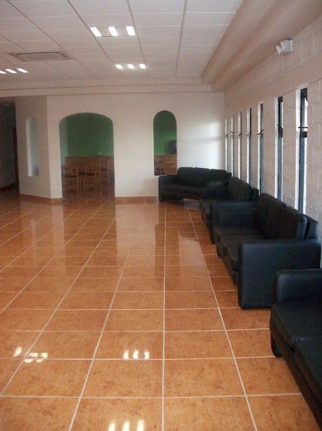Una sala de espera con suelo de baldosas y sillas negras.