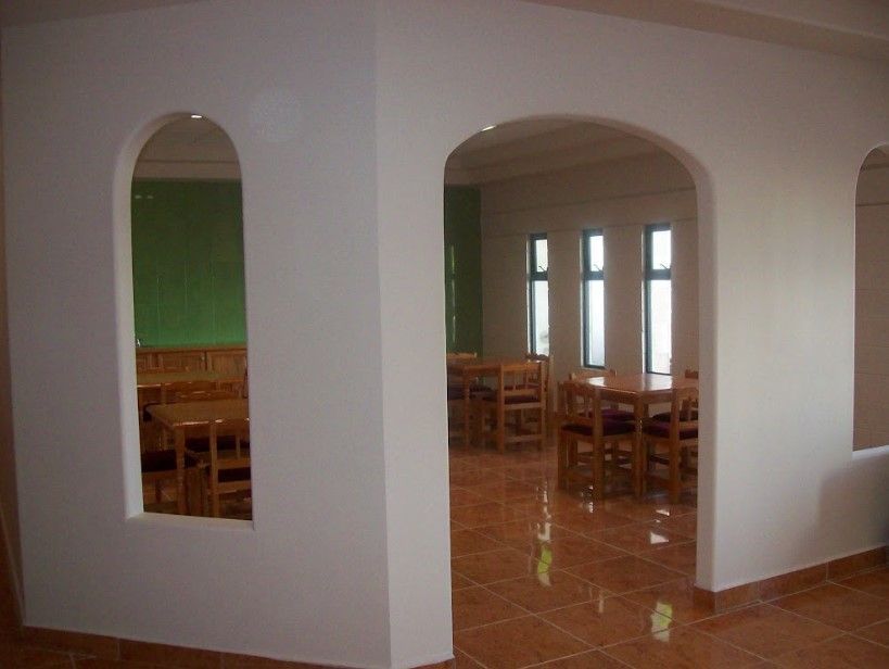 Una habitación con arcos, mesas y sillas.