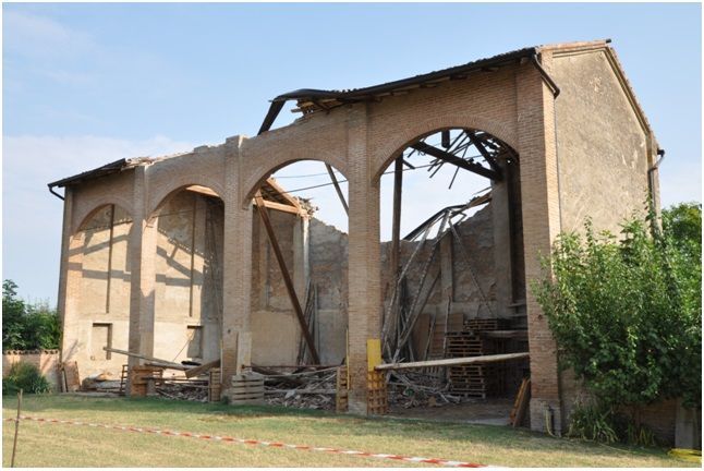 Edificio in mattoni parzialmente demolito con aperture ad arco e tetto mancante.