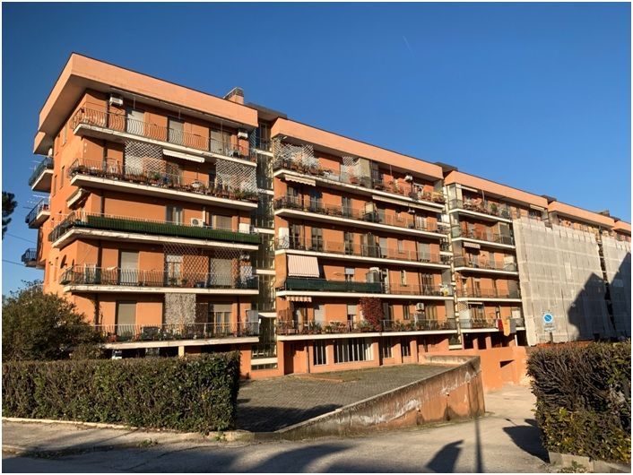 Edificio residenziale in mattoni con balconi, sotto un cielo azzurro.