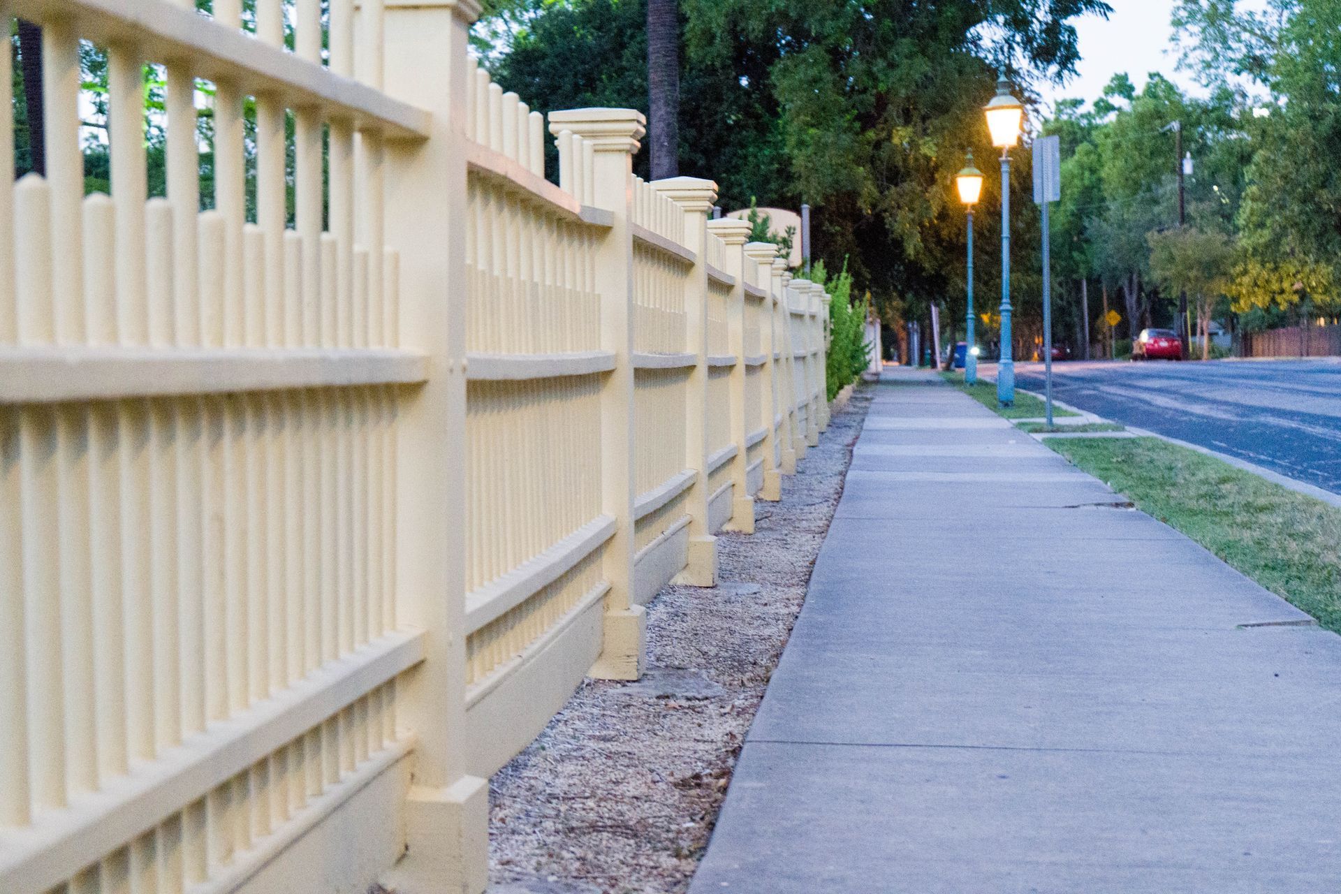 A wooden fence along a sidewalk next to a road