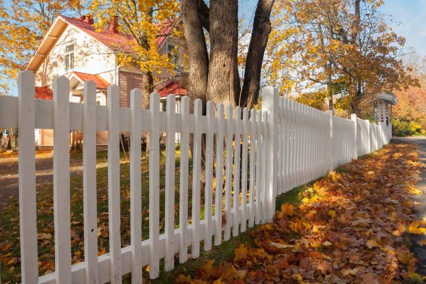 There is a white picket fence along the side of the road.