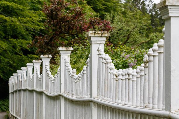 A white fence is surrounded by trees in a park.