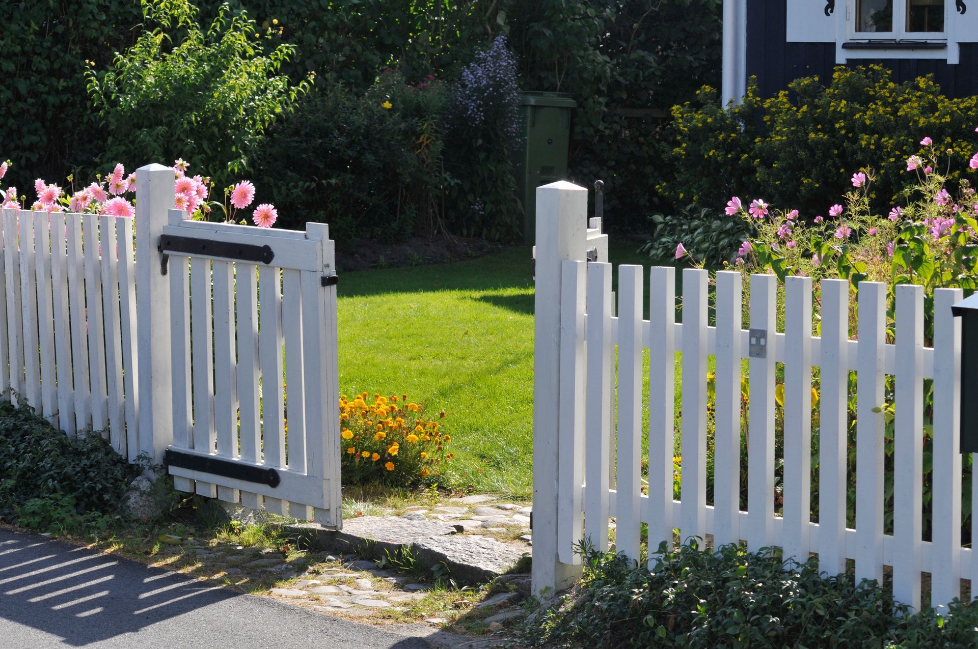 A white picket fence is surrounded by pink flowers