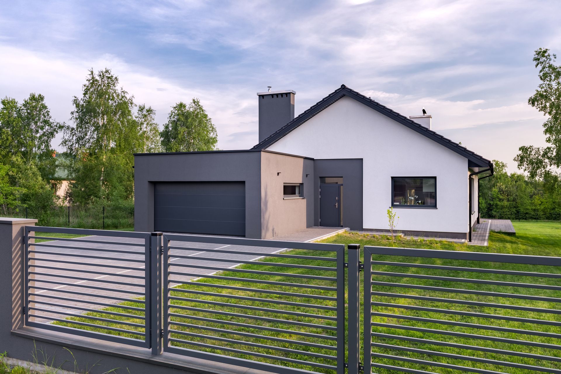 A modern house with a garage and a fence in front of it.