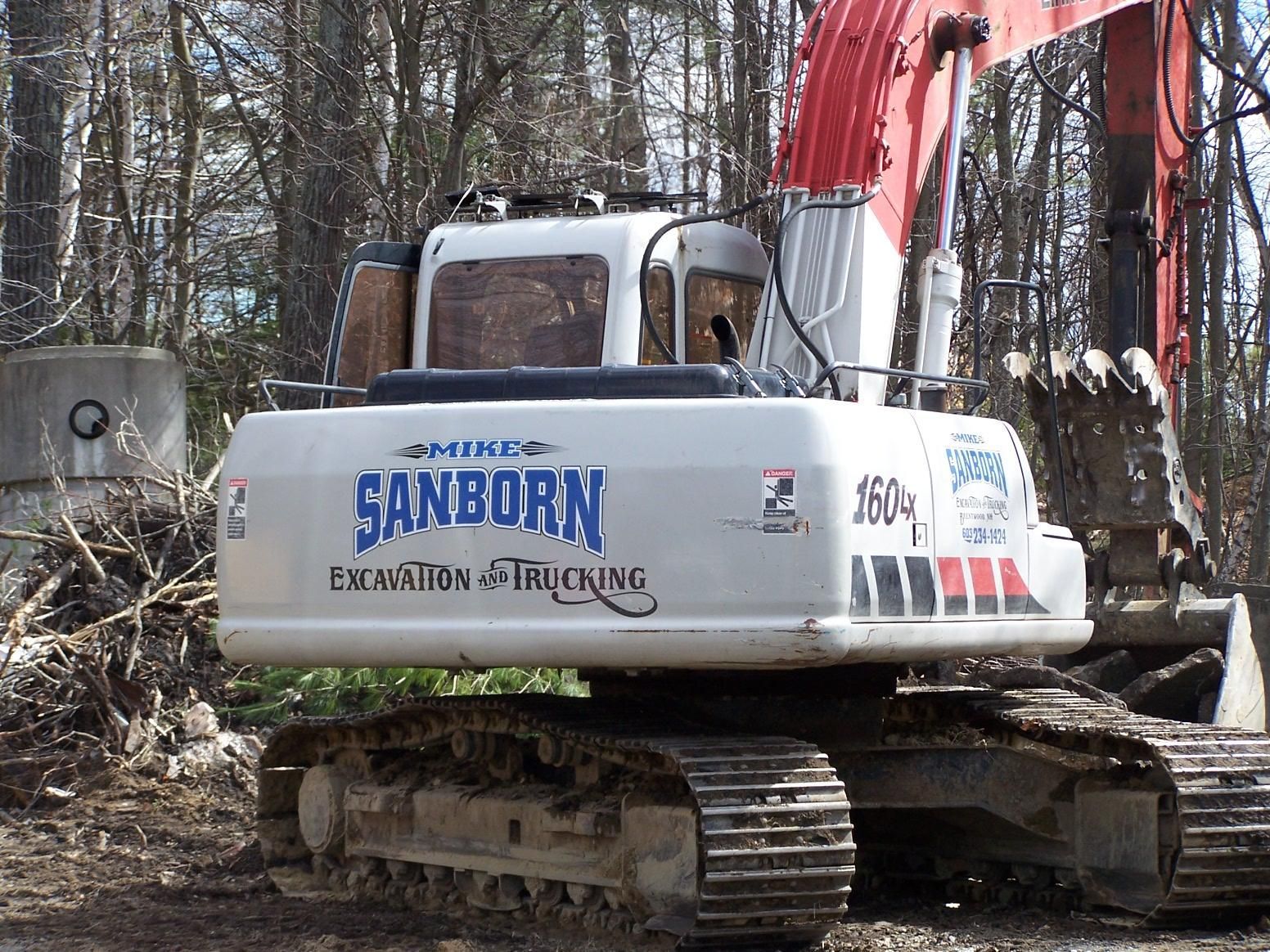 A sanborn excavator is parked in the dirt