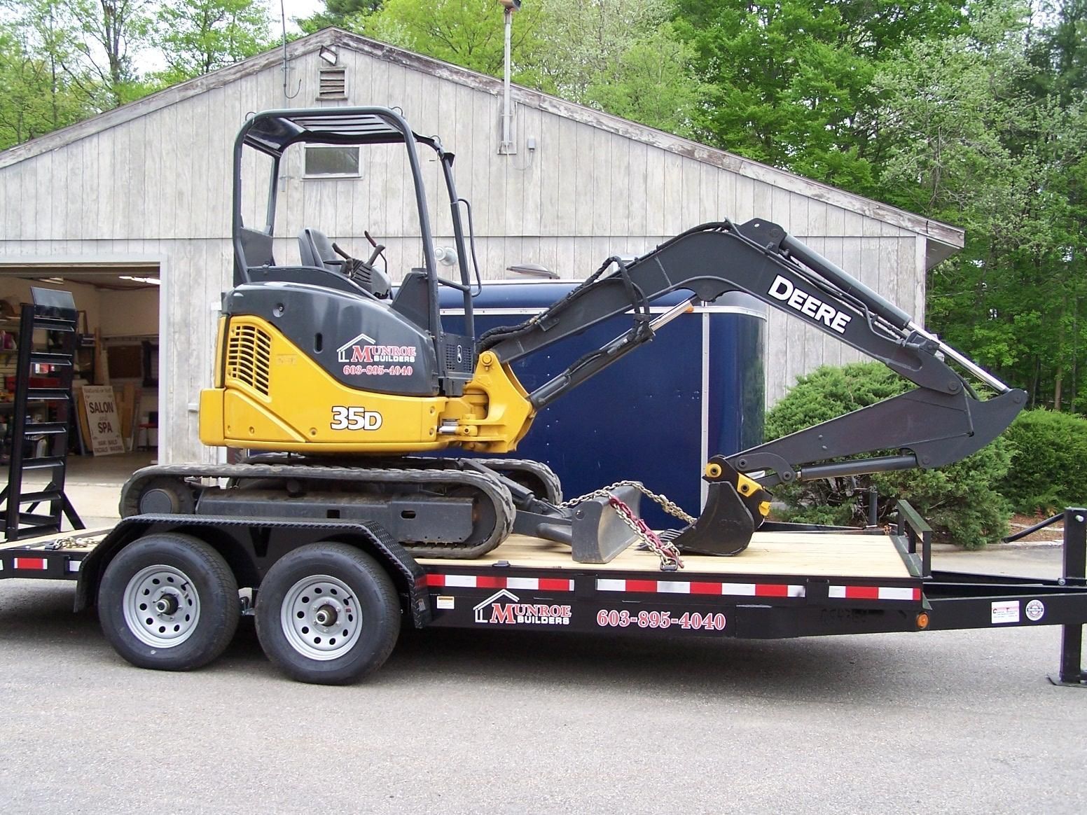 A yellow and black deere excavator on a trailer