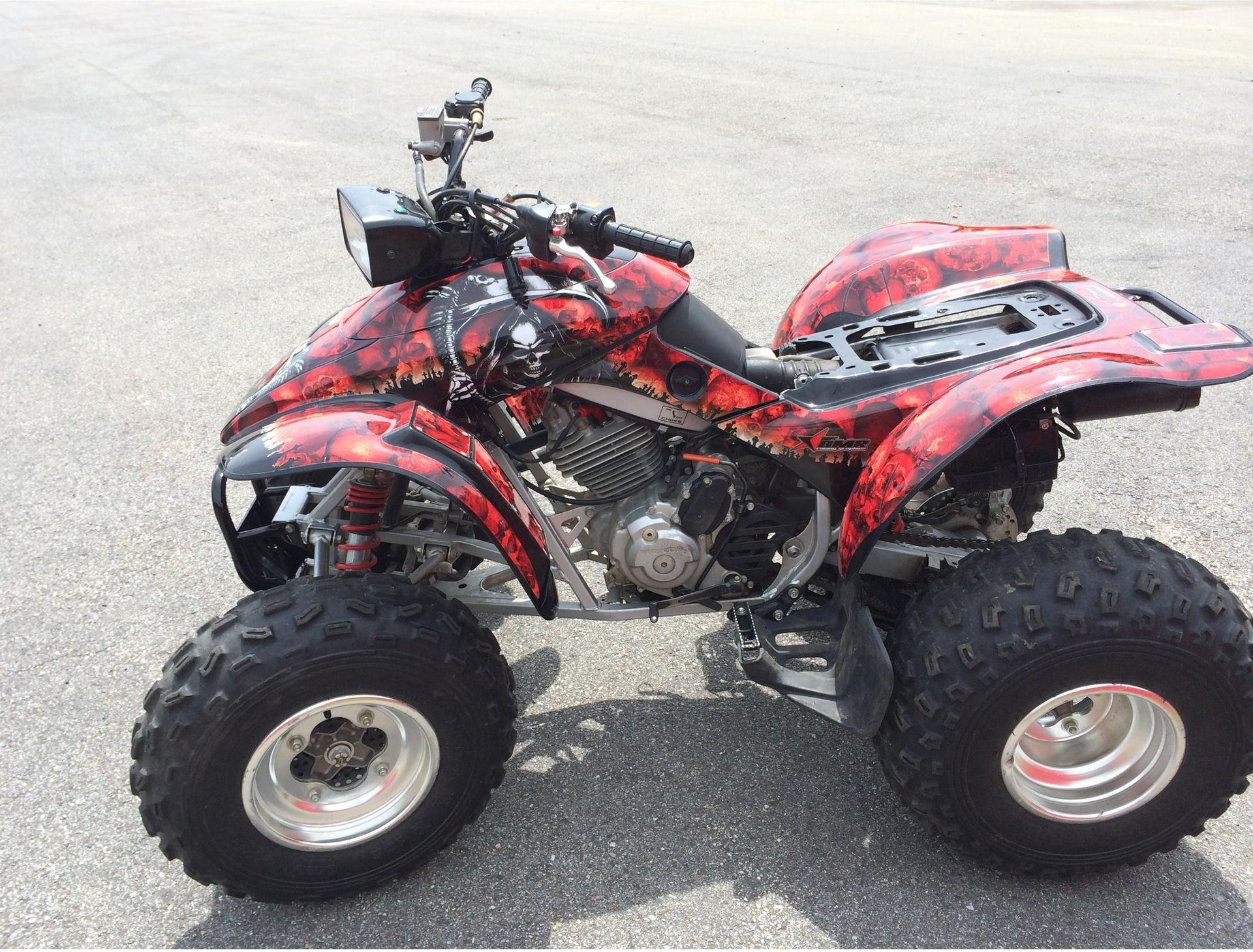 A red atv is parked on the side of the road.