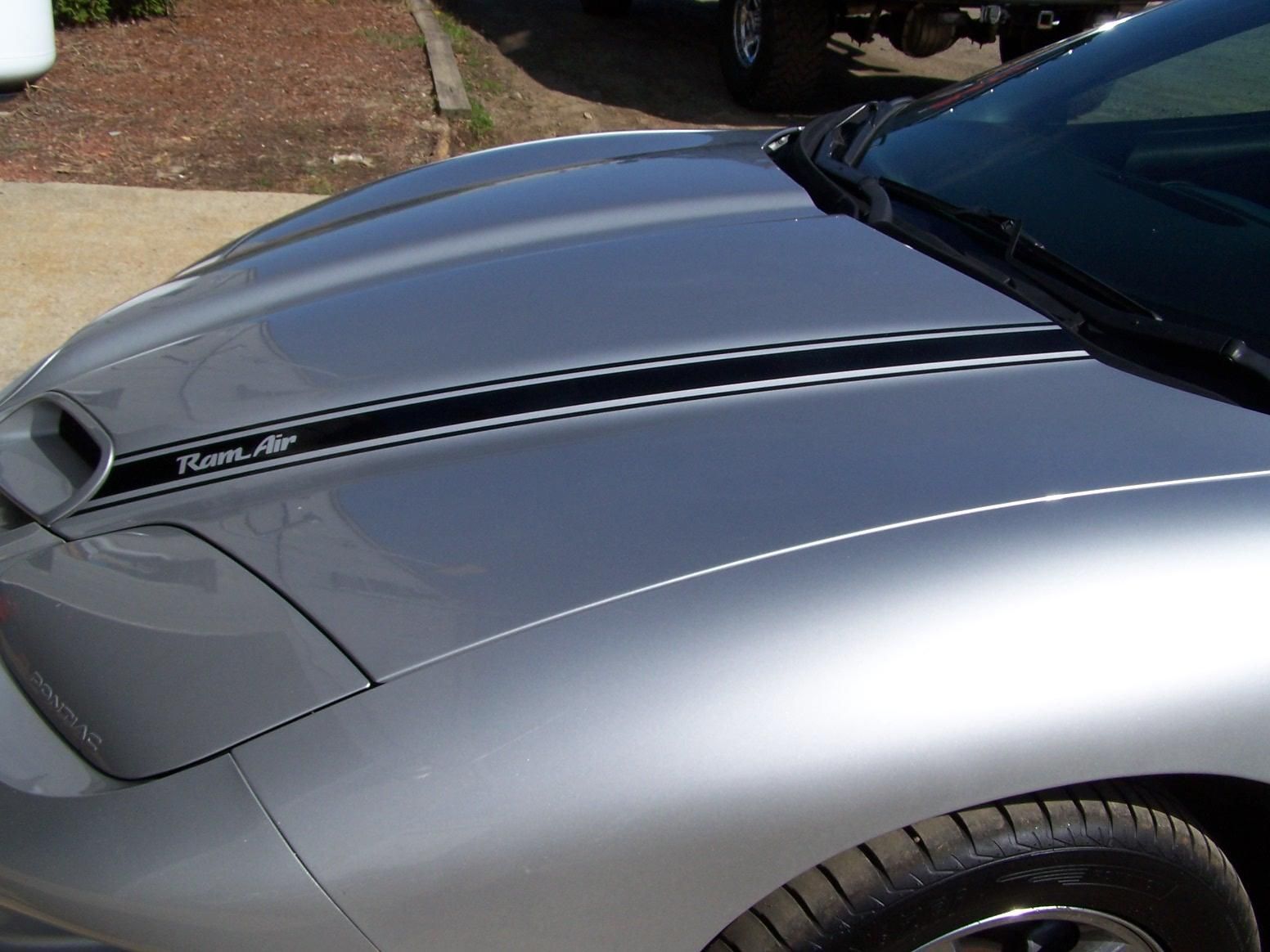 A silver car with a black stripe on the hood