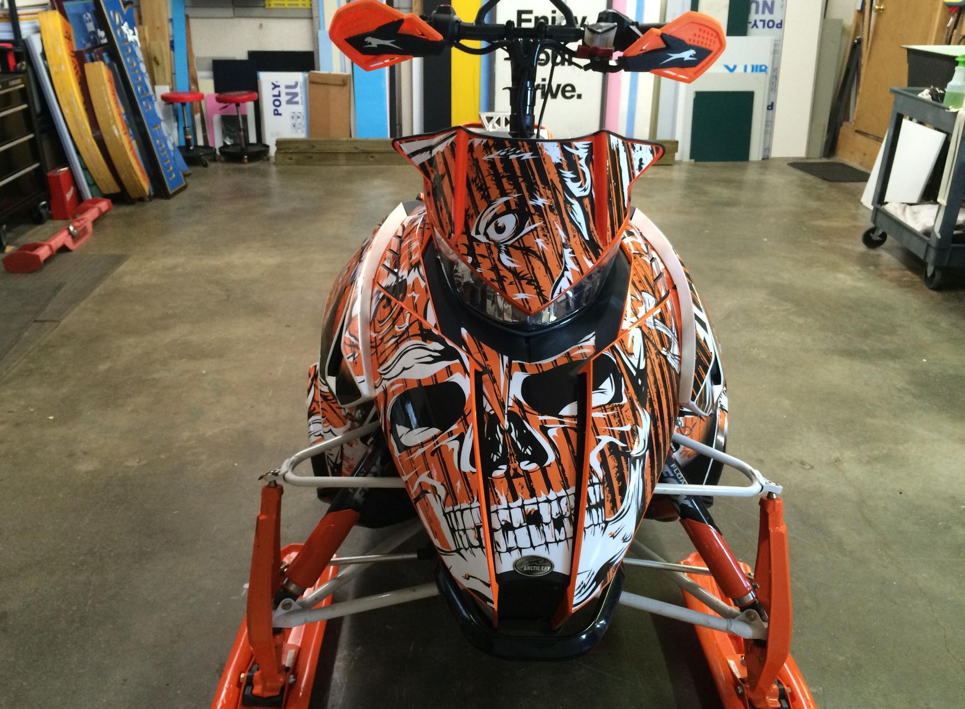 An orange and white snowmobile with a skull design on it