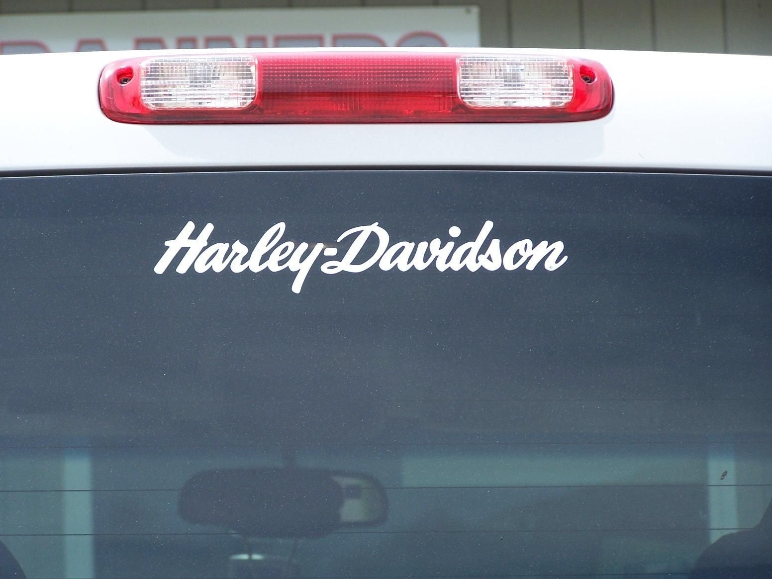 A harley davidson sticker is on the back window of a car