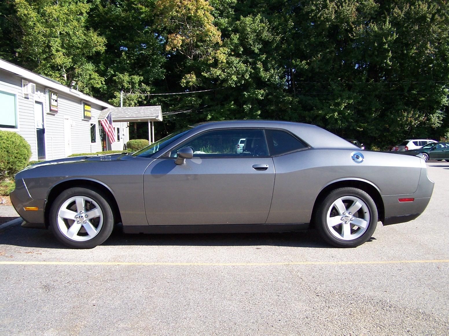 A gray dodge challenger is parked in a parking lot