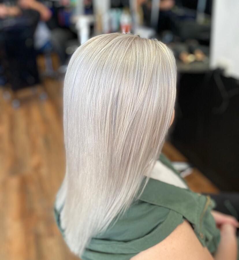 A Woman With Long White Hair is Sitting in a Chair in a Salon — Coolum Cutting Edge in Doonan, QLD