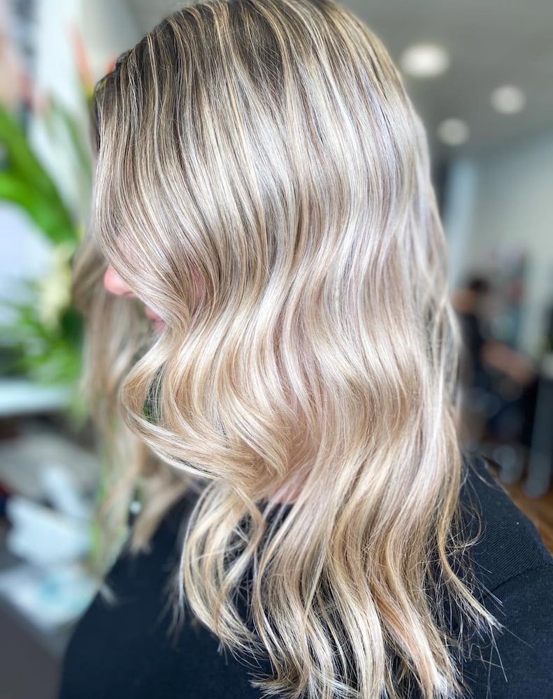 A Woman With Long Blonde Hair is Wearing a Black Shirt — Coolum Cutting Edge in Doonan, QLD