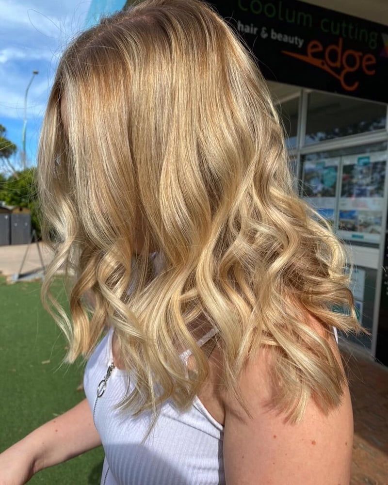 A Woman With Blonde Hair is Standing in Front of a Building — Coolum Cutting Edge in Mudjimba, QLD