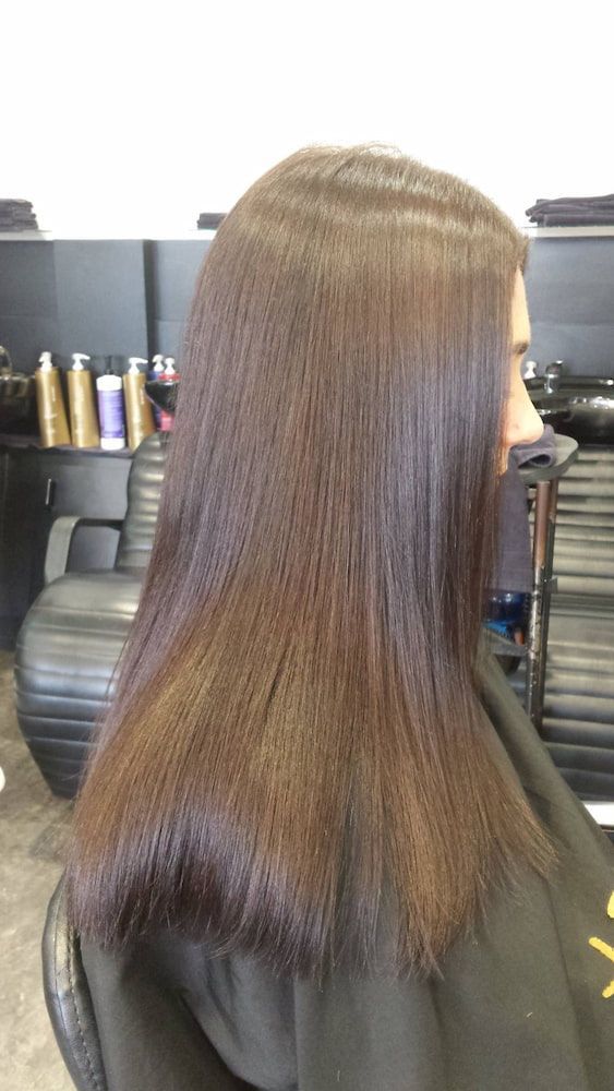 A Woman With Long Brown Hair is Sitting in a Chair at a Hair Salon — Coolum Cutting Edge in Coolum, QLD