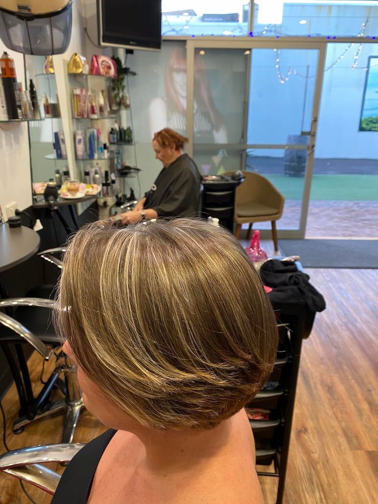A Woman is Getting Her Hair Cut in a Salon — Coolum Cutting Edge in Mudjimba, QLD
