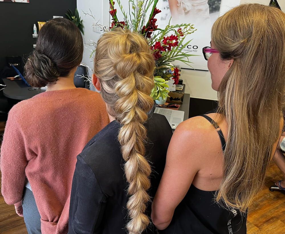 Three Women Are Standing Next to Each Other With Their Hair in a Braid — Coolum Cutting Edge in Mudjimba, QLD