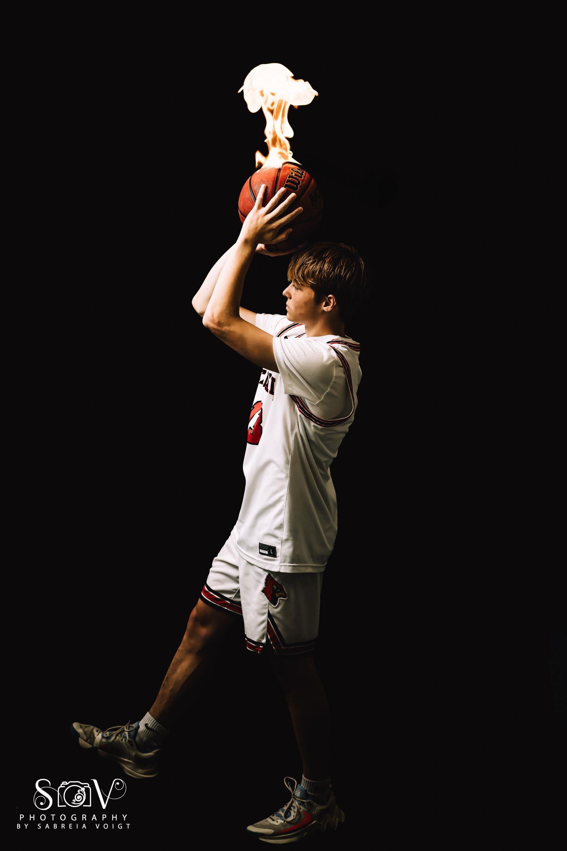 Basketball player holding a flaming ball against a black background.