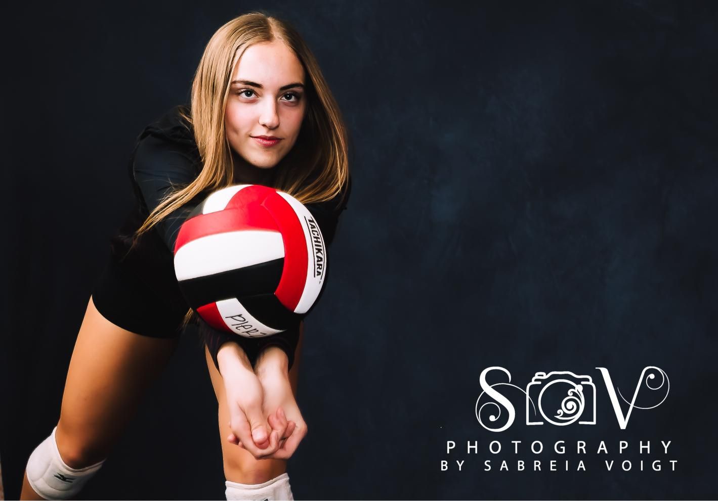 Teen volleyball player poised to bump a ball, dark background.