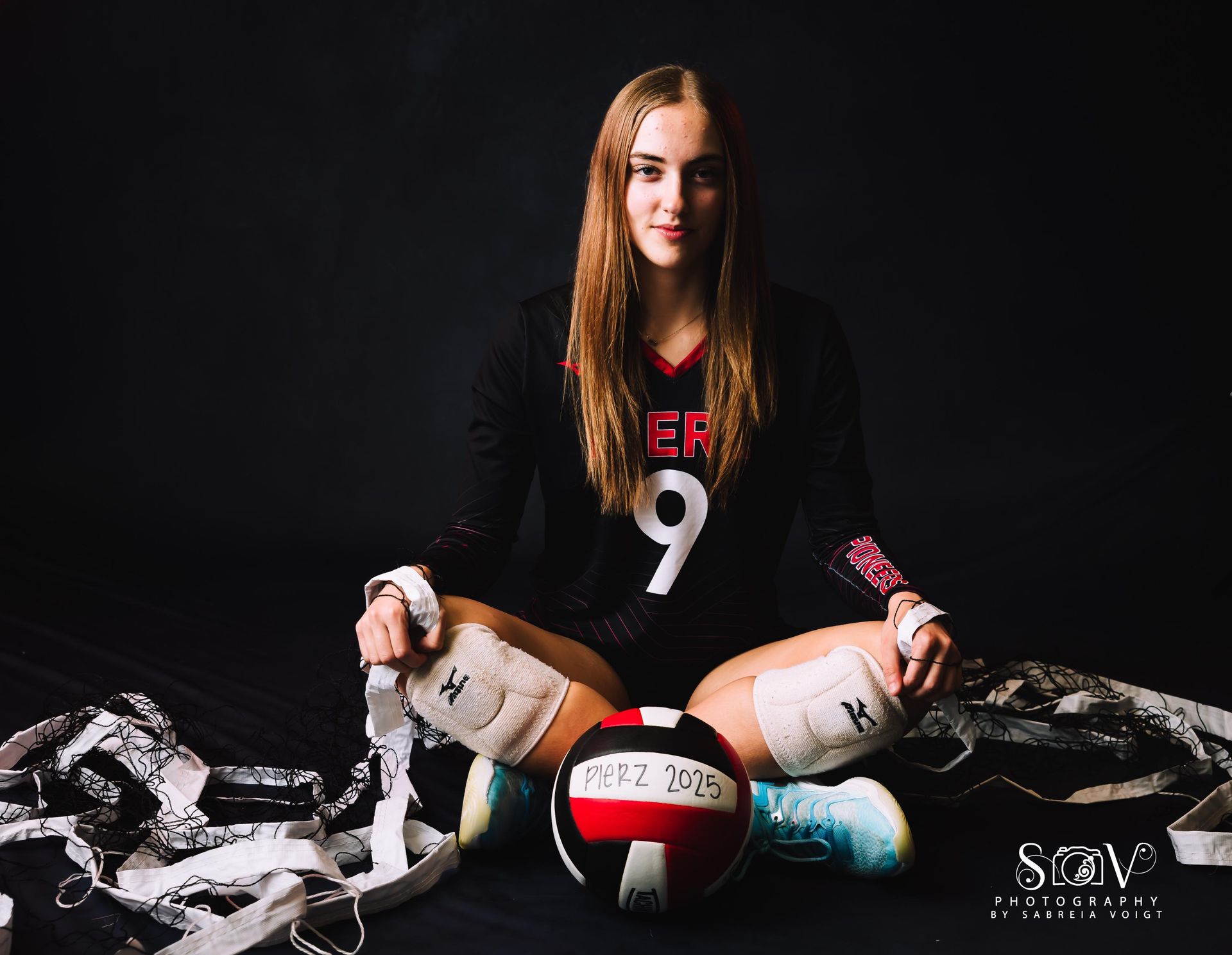 Volleyball player sitting with a ball, wearing jersey with 