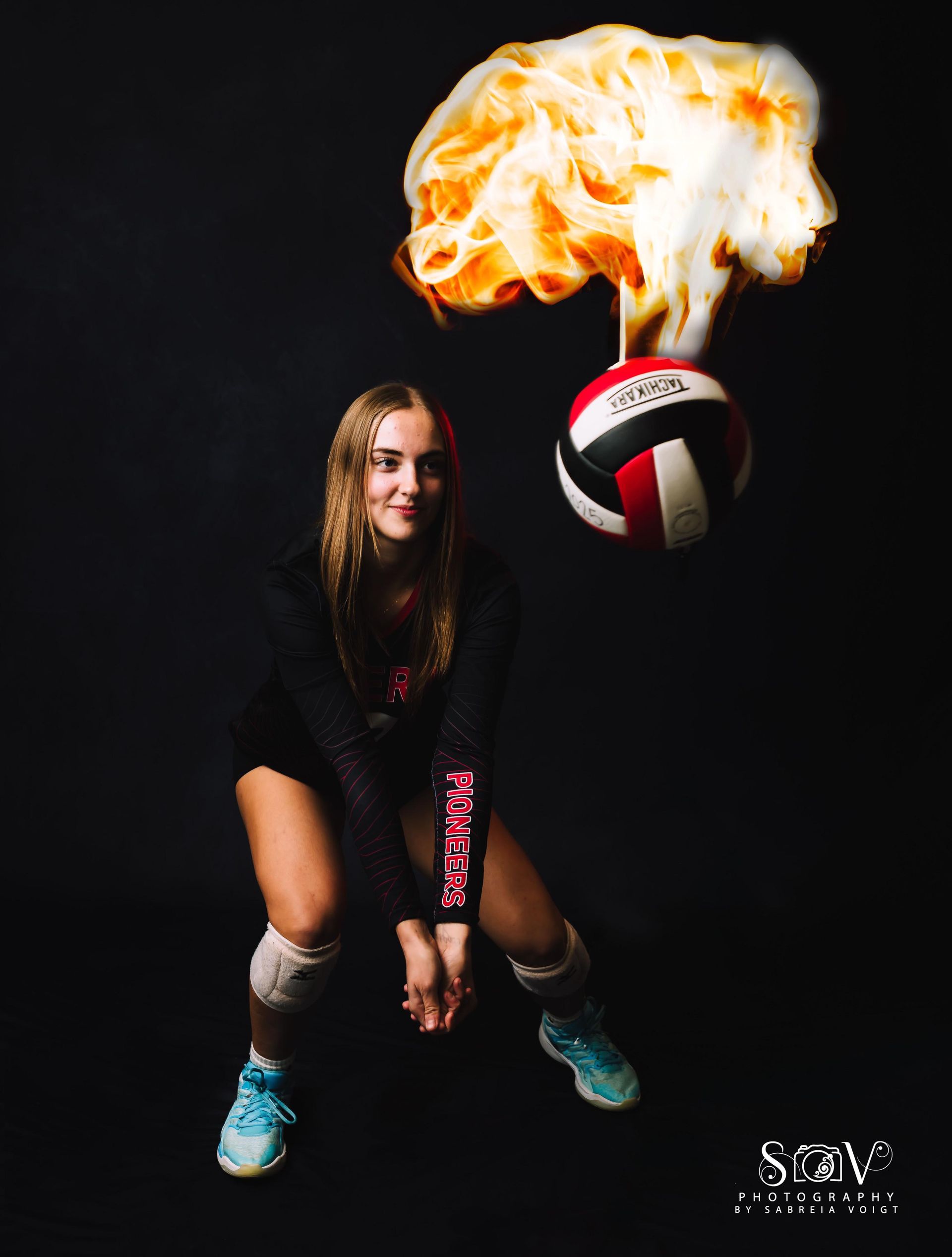 Volleyball player, in athletic pose, looks up at flaming volleyball against a black background.